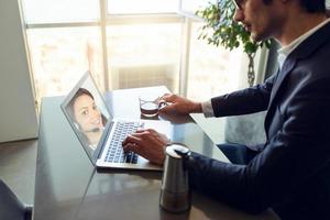 uomo d'affari lavori a partire dal a distanza a casa con il suo colleghi su il computer portatile. foto