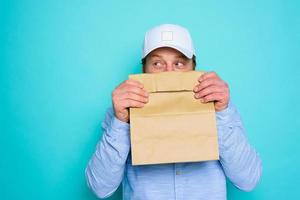 consegna uomo nasconde il suo viso con un' cibo pacchetto foto