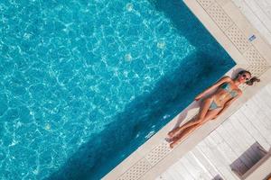 ragazza nel costume da bagno chi abbronzatura nel un' nuoto piscina foto