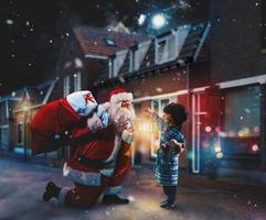 Santa Claus è dando un' presente per Natale per un' poco ragazzo foto