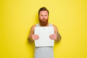 infelice uomo con barba e tatuaggi detiene un elettronico equilibrio foto