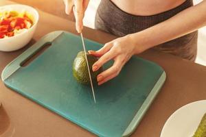 donna nel il casa cucina taglio un avocado per un' salutare mangiare foto
