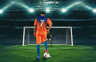 calcio scena a notte incontro con giocatore nel arancia uniforme calciando il pena calcio foto