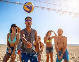 gruppo di amici giocando a spiaggia volley a il spiaggia foto