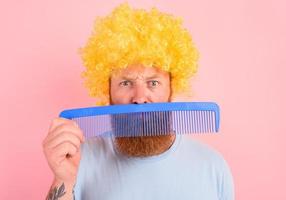 riflessivo uomo con barba, giallo parrucca e grande pettine foto