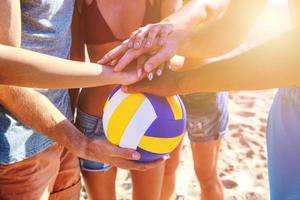 gruppo di amici giocando a spiaggia volley a il spiaggia foto