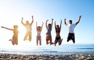 contento sorridente amici salto a il spiaggia foto