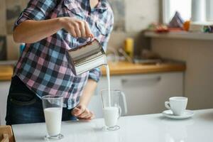 il ragazza è preparazione mattina caffè. il ragazza è preparazione prima colazione. il ragazza versa latte nel un' latte macchiato foto