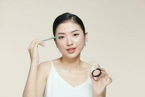 ritratto di bella asiatico donna l'applicazione cosmetici, Tenere spazzola e tavolozza, guardare e sorridente foto