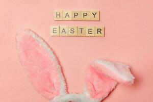 iscrizione contento Pasqua lettere decorativo coniglietto orecchie isolato su di moda pastello rosa sfondo foto