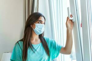 casa quarantena. caucasico donna seduta a finestra nel un' medico maschera, guardare fuori, vuole per partire fuori. protezione contro coronavirus infezione, pandemie, malattia focolai e epidemie. foto