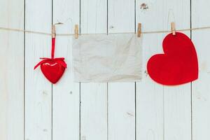 rosso cuore e vecchio carta vuoto sospeso a clothesline su legna bianca sfondo con spazio. San Valentino giorno. foto