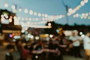 sfocato sfondo a notte mercato Festival persone a piedi su strada. foto