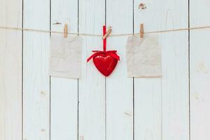 rosso cuore e vecchio carta vuoto sospeso a clothesline su legna bianca sfondo con spazio. San Valentino giorno. foto