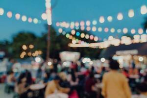 sfocato sfondo a notte mercato Festival persone a piedi su strada. foto