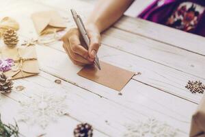 donna mano scrittura bellissimo Natale carta a tavolo foto