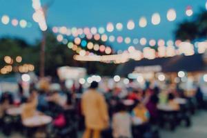 sfocato sfondo a notte mercato Festival persone a piedi su strada. foto