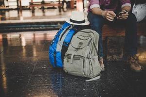 uomo giovane hipster seduto sulla panchina alla stazione ferroviaria foto