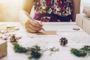 donna mano scrittura bellissimo Natale carta a tavolo foto