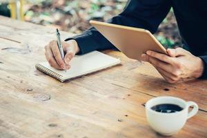 attività commerciale uomo mano scrittura Nota tampone e Tenere tavoletta nel caffè negozio con Vintage ▾ filtro. foto