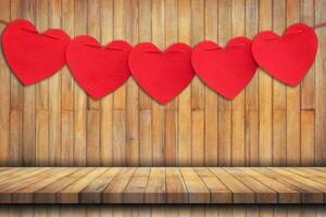 rosso cuore sospeso su legna tavolo sfondo e struttura verticale. foto