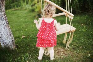 ragazza nel il giardino giocando con altalene. bambino giocando nel il giardino solo foto