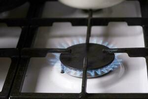 accensione di il gas bruciatore su il stufa nel il cucina. uso di naturale risorse, economia, cucinando su fuoco. avvicinamento foto