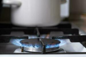 accensione di il gas bruciatore su il stufa nel il cucina. uso di naturale risorse, economia, cucinando su fuoco. avvicinamento foto
