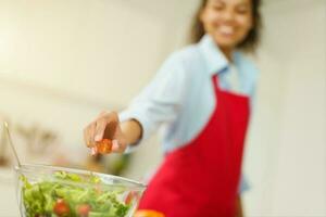 giovane cucinare con grembiule prepara un' insalata nel il cucina foto