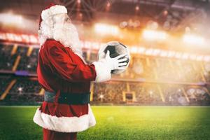 Santa Claus con un' calcio palla nel il suo mani dentro un' calcio stadio foto
