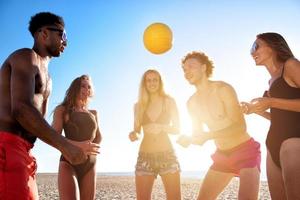 gruppo di amici giocando a spiaggia volley a il spiaggia foto