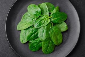 fresco verde spinaci le foglie su un' nero ceramica piatto foto