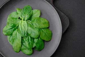 fresco verde spinaci le foglie su un' nero ceramica piatto foto