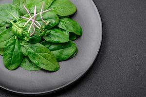 fresco verde spinaci le foglie su un' nero ceramica piatto foto