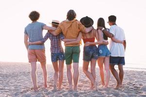 gruppo di contento amici avendo divertimento a oceano spiaggia foto