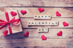 regalo scatola e rosso cuore con di legno testo contento San Valentino giorno su legna tavolo sfondo. foto