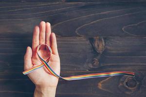 arcobaleno nastro consapevolezza su mano umano per lgbt concetto su di legno sfondo. foto