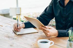 attività commerciale uomo mano Tenere tavoletta e scrittura taccuino nel caffè negozio. foto