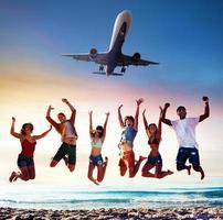 contento sorridente amici salto su il spiaggia con un aereo su il cielo foto