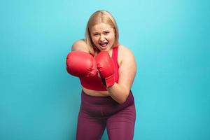 Grasso ragazza nel fitness suite fa boxe. ciano sfondo foto