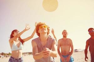 gruppo di amici giocando a spiaggia volley a il spiaggia foto