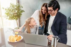 contento poco ragazza Guardando un' film su il computer con sua padre e madre foto