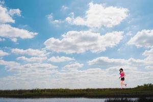 in esecuzione ragazza su un' verde campo e luminosa cielo foto