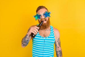 uomo con barba e occhiali da sole bevande birra foto