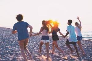 gruppo di contento amici avendo divertimento a oceano spiaggia foto