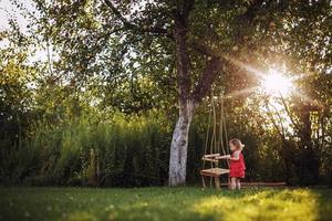 ragazza nel il giardino giocando con altalene. bambino giocando nel il giardino foto