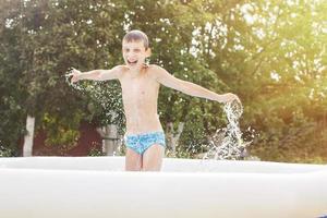 contento ragazzo avendo divertimento nel il nuoto piscina con padre nel il giardino a estate foto