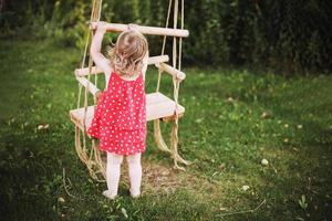 ragazza nel il giardino giocando con altalene. bambino giocando nel il giardino solo foto