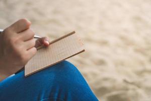 donna mano che scrive in un piccolo taccuino memo foto