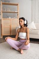 mentale benessere concetto.verticale bandiera con africano americano donna Meditare a casa ascoltando per musica foto